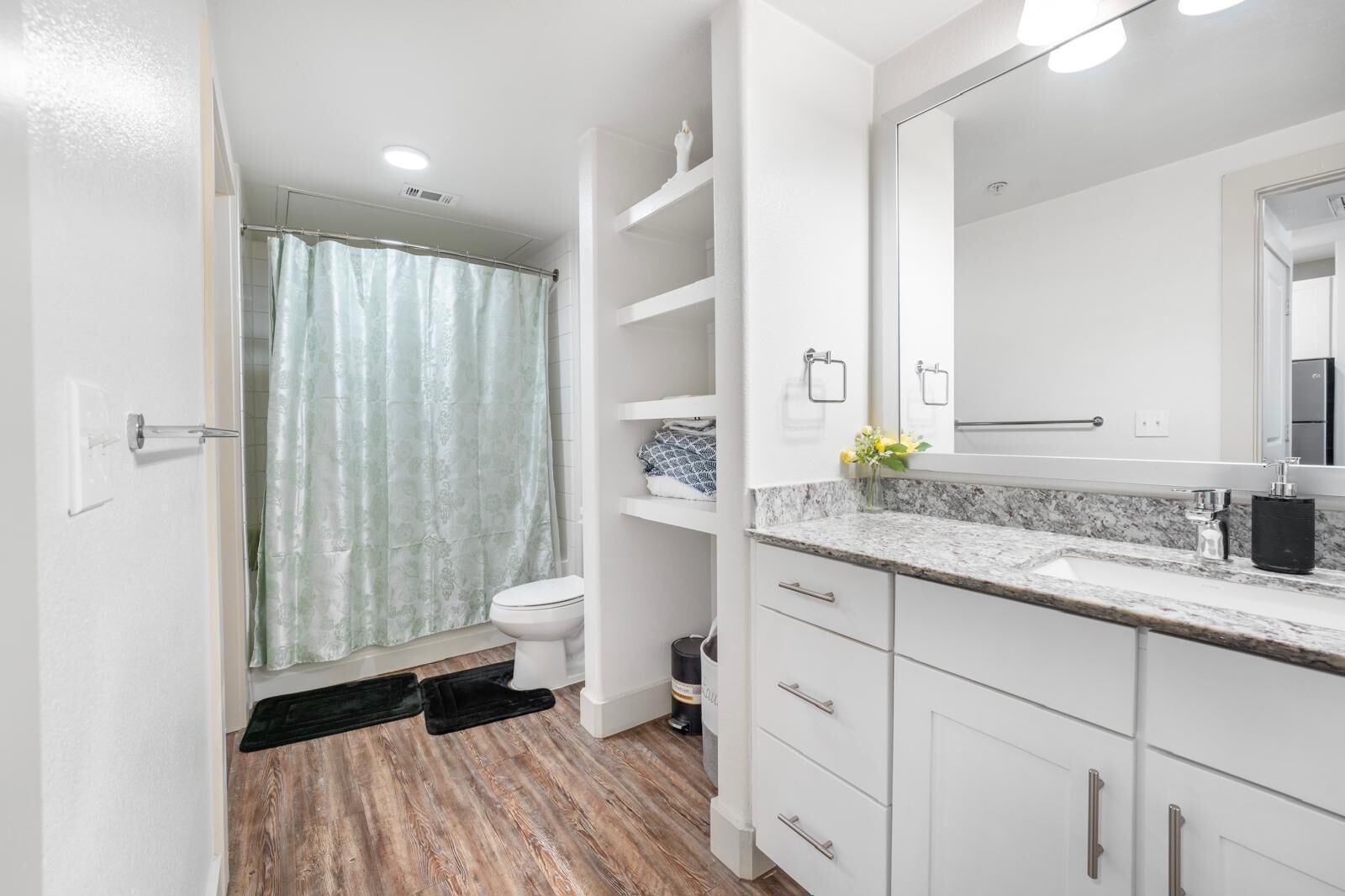 A modern bathroom with a shower, toilet, and vanity with a large mirror.