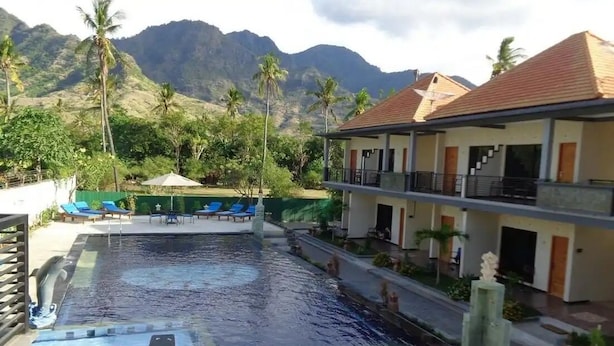 A hotel with a swimming pool, lounge chairs, and a view of mountains. - Hidden Hotel Pemuteran (Pemuteran)