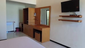 A modern bedroom with a wooden vanity, a large mirror, a television mounted on the wall, and a small desk. - Hidden Hotel Pemuteran (Pemuteran)
