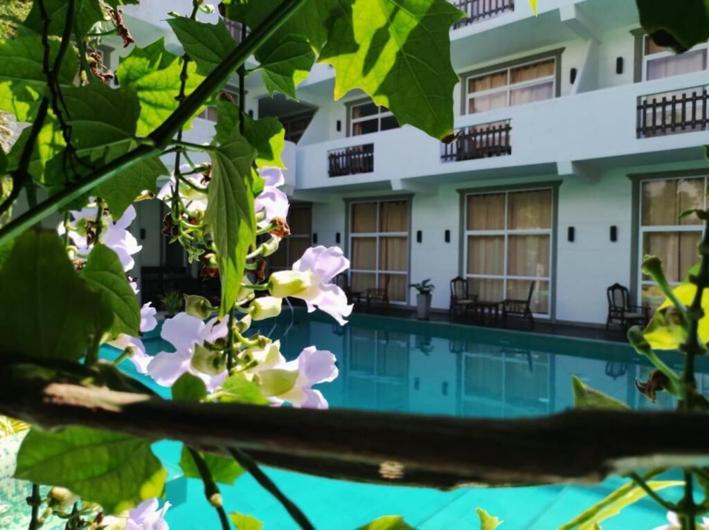A hotel with a swimming pool, balconies, and a view of the pool.
