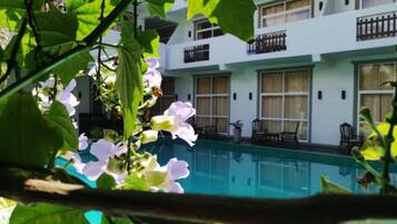 A hotel with a swimming pool, balconies, and a view of the pool.