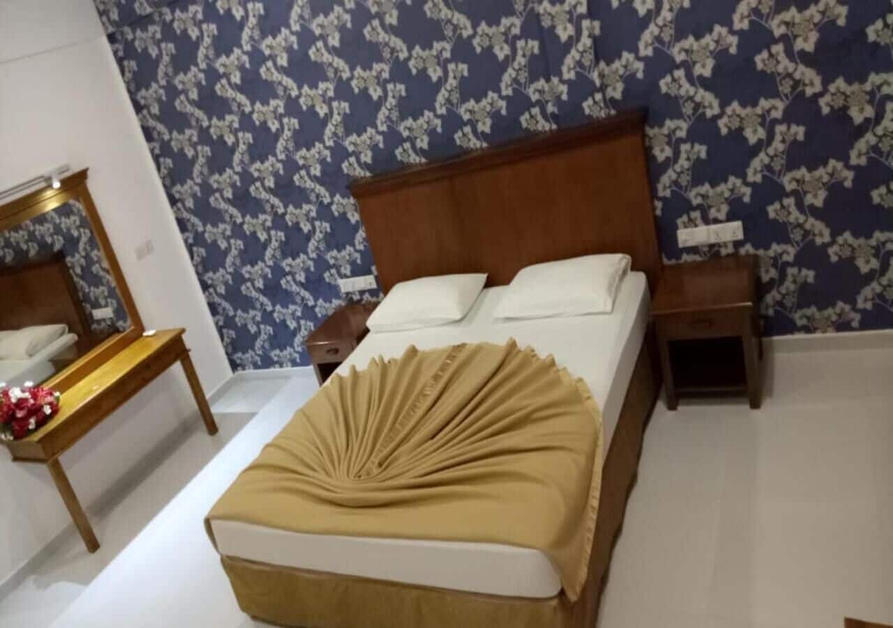 A bedroom with a bed, wooden headboard, bedside tables, and a mirror.