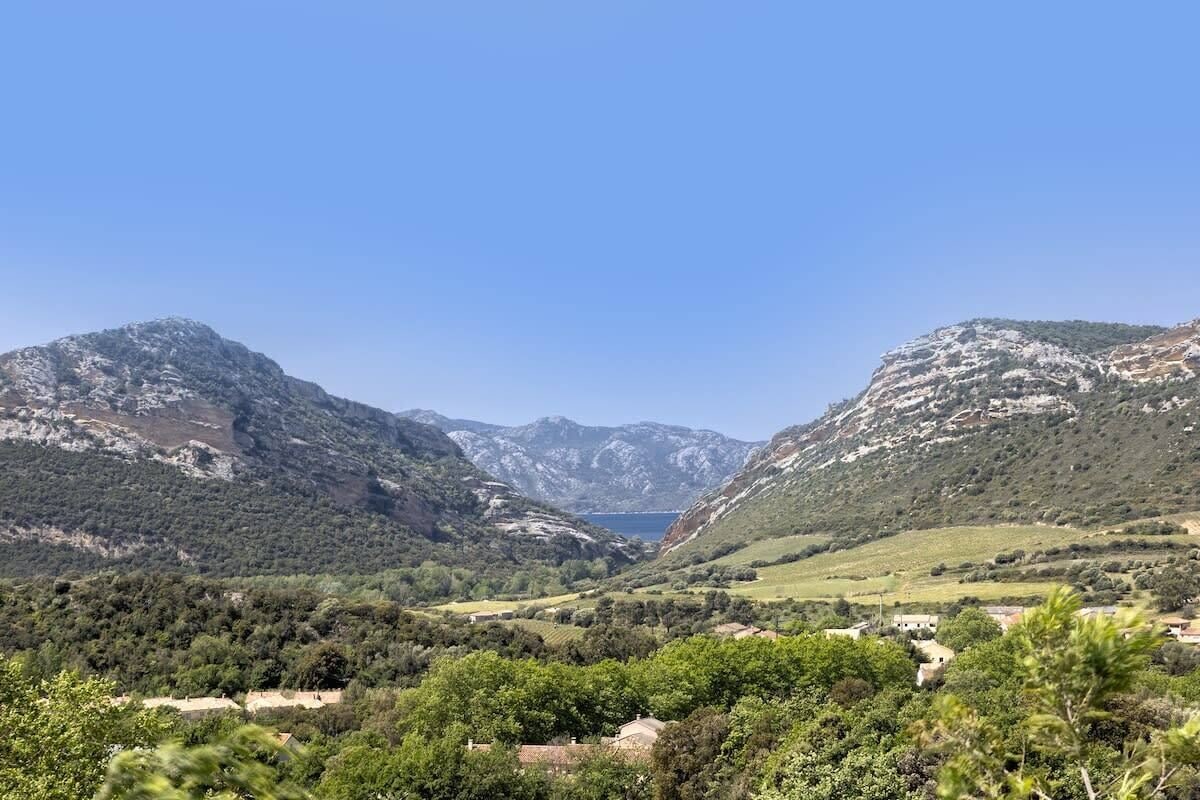 Un paysage montagneux comprenant une vallée, un lac et quelques bâtiments dispersés.