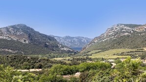 Eine gebirgige Landschaft mit einem Tal, einem See und verstreuten Gebäuden.