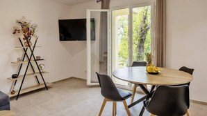 Un espace repas moderne avec une table ronde, des chaises noires et un saladier à fruits.