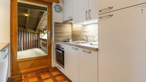 Eine kleine Küche mit Holzausstattung, einem eingebauten Backofen und einem Spülbecken.