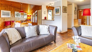 Ein gemütliches Zimmer mit einer braunen Ledersofa, einem Holzesstisch und einer roten Lampe.
