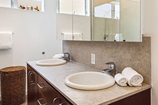Un baño con dos lavamanos, un espejo grande y un perchero para toallas.