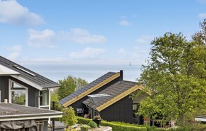 A modern house with a sloped roof, a visible chimney, and a view of the sea.