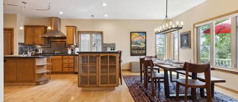 A spacious kitchen with wooden cabinets, a large island, and a dining area with a rug and chairs.