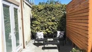 A patio with a seating area, a wooden fence, and a garden wall. - Central Saanich cozy suite

 (Victoria)
