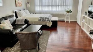 A modern living room with a sofa, a chair, a bed, and a TV. - Central Saanich cozy suite

 (Victoria)