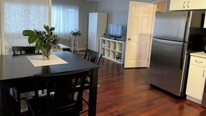 A compact kitchen with a refrigerator, a dining table with chairs, and a television on a stand. - Central Saanich cozy suite

 (Victoria)