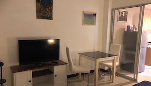 Cozy living space with a flat-screen TV, dining table, and sliding door to the kitchen.