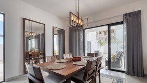 Une salle à manger moderne avec une table en bois, des chaises et un lustre.