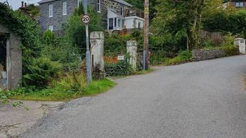 Une rue résidentielle avec un panneau indiquant la limite de vitesse, des maisons et une végétation luxuriante.
