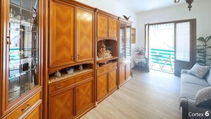 Een ruime woonkamer met een grote houten kast, een bank en een balkon met uitzicht.
