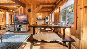 Ambiente in legno con tavolo da pranzo, TV e angolo cottura.