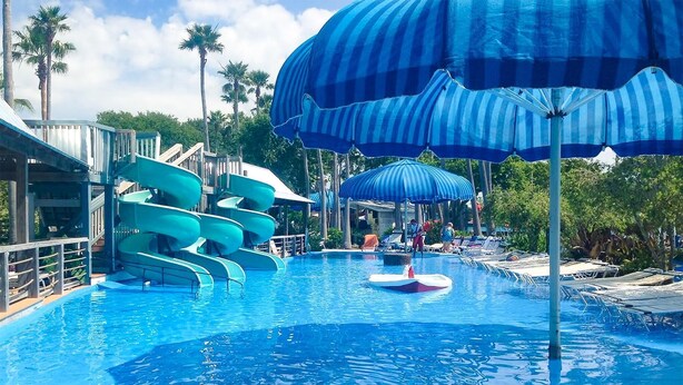 A swimming pool with multiple slides and umbrellas.