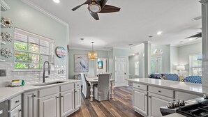 A modern kitchen with white cabinetry, a central island, and a dining area with a table and chairs.