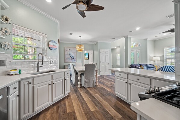 A modern kitchen with white cabinetry, a central island, and a dining area with a table and chairs.
