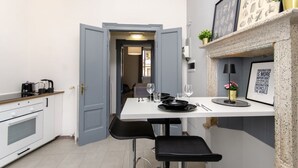 A compact kitchen with a dining area, a white table, and a blue door leading to another room. - VivimiHome - [Navigli-Duomo] Maison Fusetti (Milano)