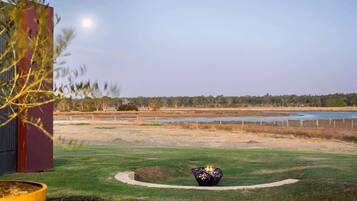 A landscaped outdoor area with a fire pit, a pond, and a building in the background.
