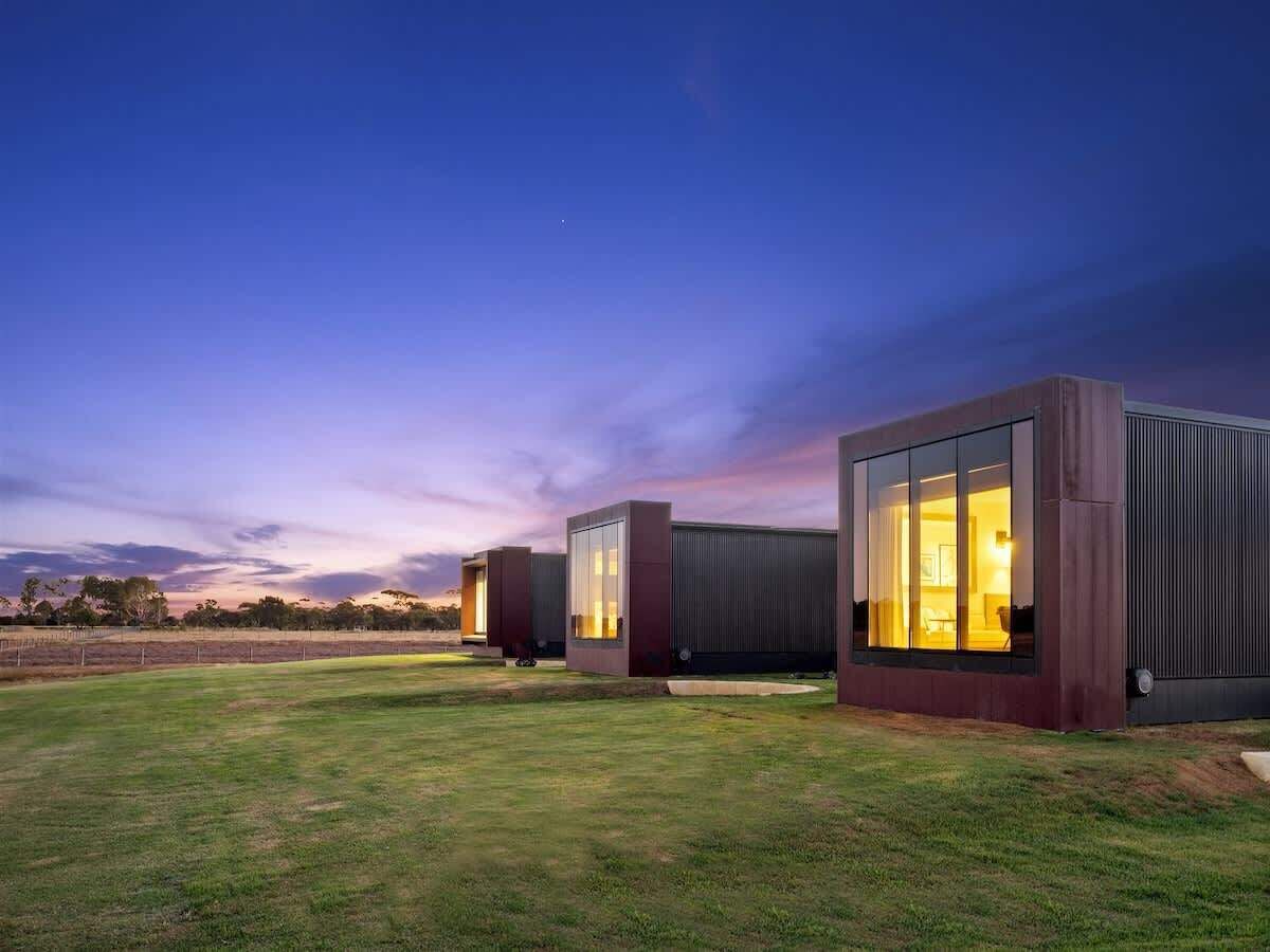 A modern building with large windows and a flat roof, surrounded by a grassy area.