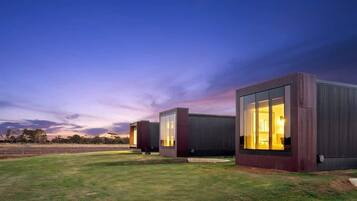 A modern building with large windows and a flat roof, surrounded by a grassy area.