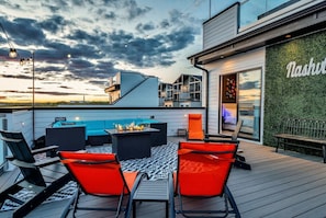Una terraza al aire libre con una chimenea, asientos y una zona junto a la piscina.