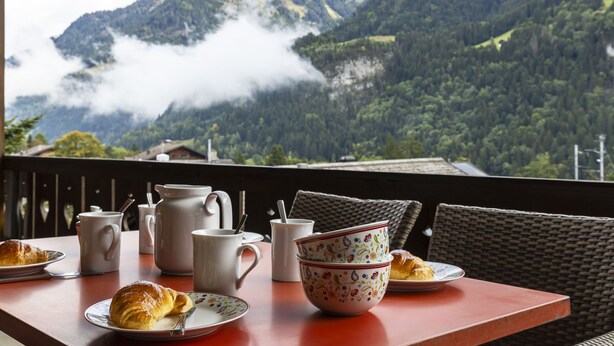 A table with breakfast items and a scenic mountain view.