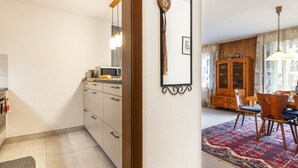 A modern kitchen with a microwave, a wooden cabinet, and a dining area with a table and chairs.