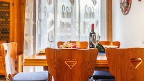 A dining area with wooden chairs, a table, and a bottle of wine.