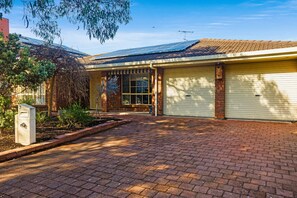 A building with a brick driveway, a garage with a closed shutter, and a mailbox.