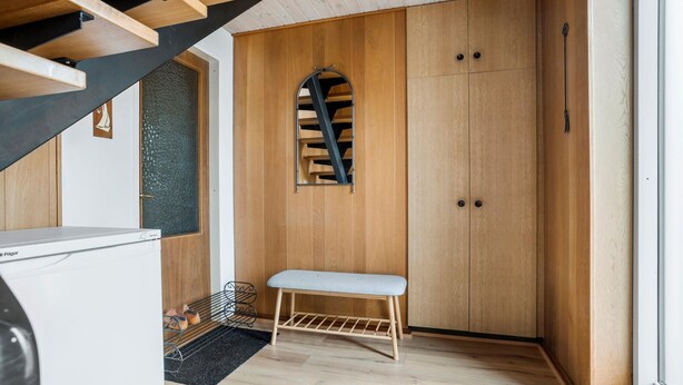 A compact room with a wooden wardrobe, a bench, a washing machine, and a small window with a view of a staircase. - Lovely apartment in Erslev with WiFi (Erslev)