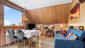 A dining area with a table and chairs, a blue sofa, and a wooden ceiling. - Lovely apartment in Erslev with WiFi (Erslev)