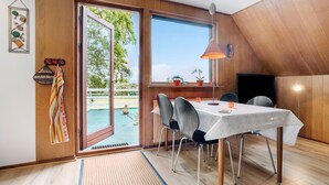 A dining area with a table, chairs, and a view through a sliding glass door to an outdoor space with plants. - Lovely apartment in Erslev with WiFi (Erslev)