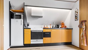 A compact kitchen with a microwave, stove, and oven. There are orange cabinets and a black countertop. A coffee maker and a kettle are on the counter. - Lovely apartment in Erslev with WiFi (Erslev)
