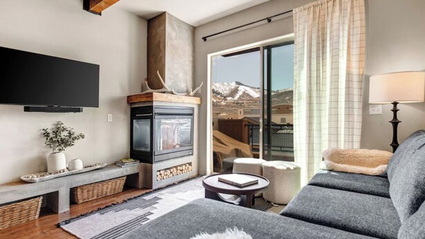 Ein modernes Wohnzimmer mit Kamin, einer Couch, einem Couchtisch und einem an der Wand befestigten Fernseher.