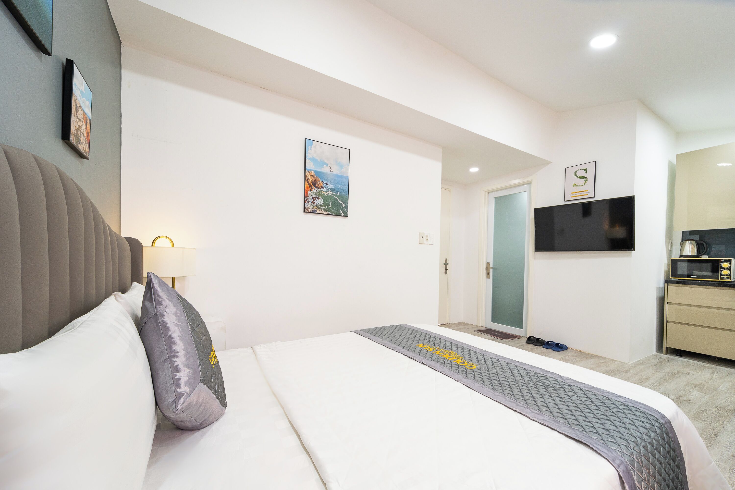 Una habitación de hotel con una cama, televisor, escritorio y puerta.