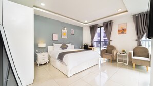 A modern bedroom with a large bed, bedside tables, a small side table, and two armchairs. - Golden Suites 3 Apartments (Ho Chi Minh City)