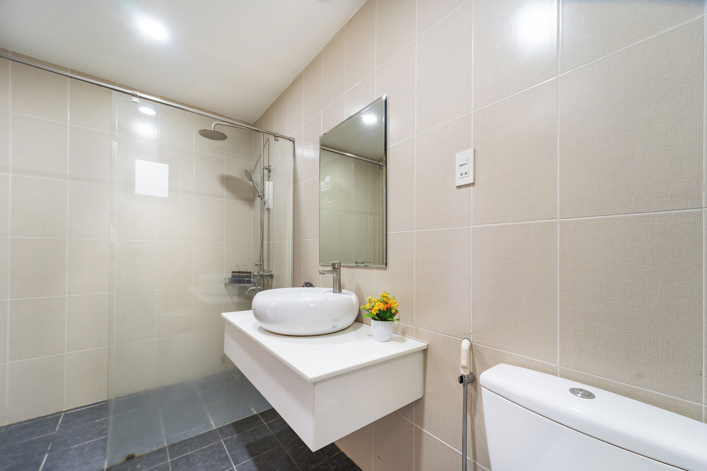 Ein modernes Badezimmer mit Duschkabine, Waschbecken, Spiegel und Toilette.