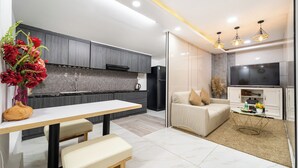A modern kitchen with grey cabinets, a white countertop, and a dining area with a bench. - Golden Suites 3 Apartments (Ho Chi Minh City)