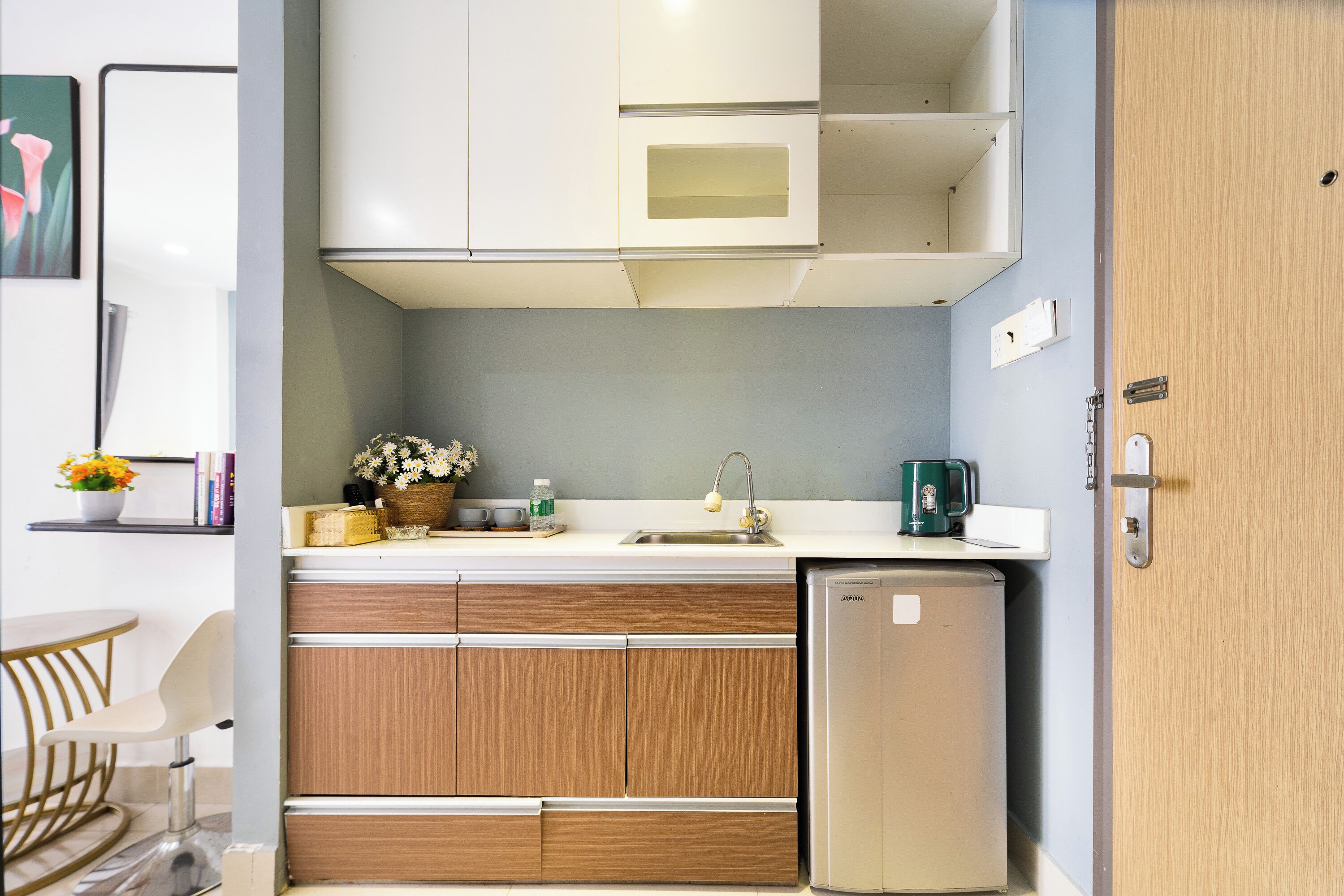 A compact kitchen with wooden cabinets, a stainless steel sink, and a small refrigerator.