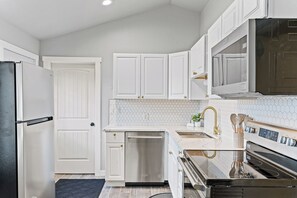 Una cocina moderna con armarios blancos, electrodomésticos de acero inoxidable y un protector contra salpicaduras de azulejos.