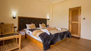 Un dormitorio con cama de madera, mesitas de noche, una silla de madera y una puerta de madera.