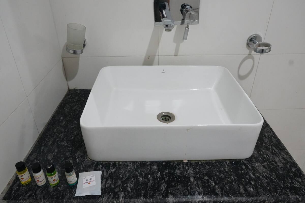 A bathroom with a white sink, a marble countertop, and a faucet. There are four bottles of hand soap on the counter.
