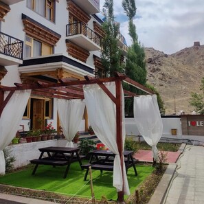 A hotel with a balcony, outdoor seating, and a view of a mountainous landscape. - Marigold Ladakh (Leh)