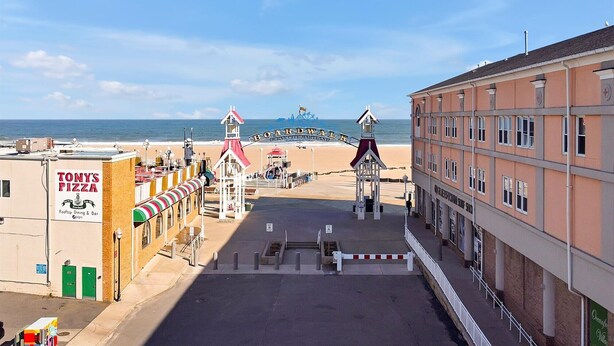 A boardwalk with Tony's Pizza, a beach, and a building with a sign reading "Oceanfront Villa." - OCHG OF Villas (Ocean City)