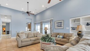 A spacious living room with a beige sectional sofa, a coffee table with a plant, and a ceiling fan. - OCHG OF Villas (Ocean City)